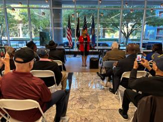 Rep. McBath stands at a podium, addressing Vietnam veterans and their families.