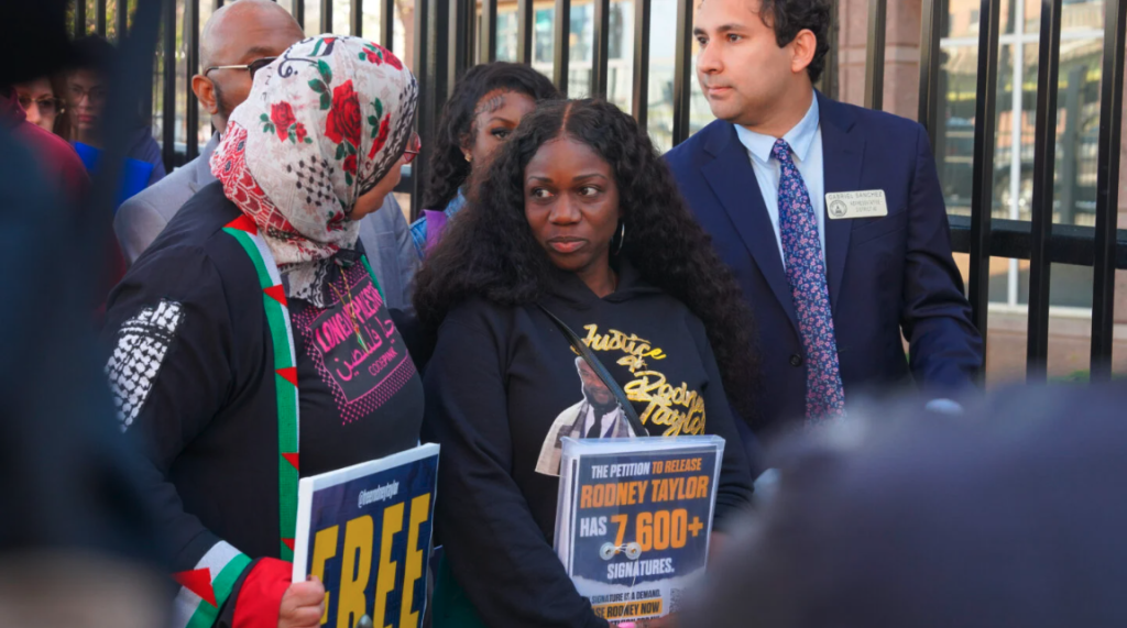 Photo: Mildred Taylor, whose husband has been in detained at Stewart Detention Center for over a year, stands in line in front of the ICE field office in Atlanta, Ga to deliver over 7,600 petitions demanding her spouses release. (Matthew Pearson/WABE)